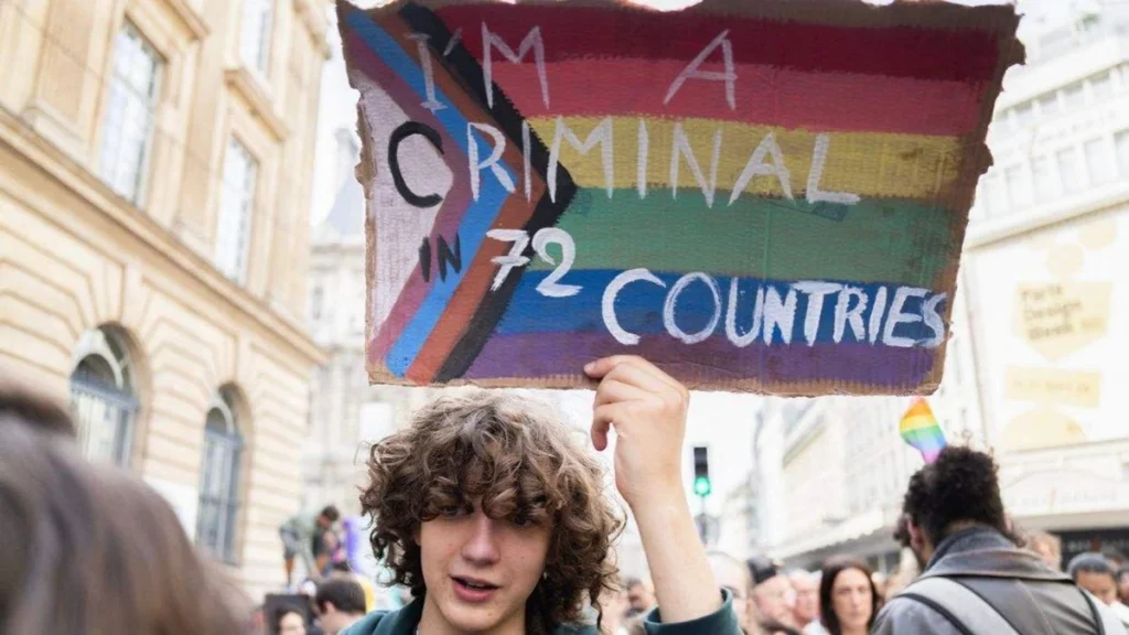 A marcher holds a hand-painted Progress Pride sign at a Pride march in Paris