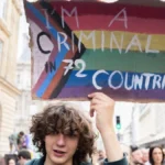 A marcher holds a hand-painted Progress Pride sign at a Pride march in Paris
