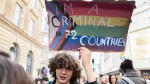 A marcher holds a hand-painted Progress Pride sign at a Pride march in Paris